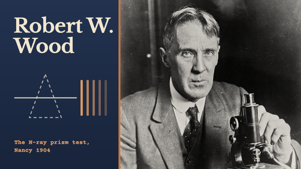 Robert W. Wood at a microscope in a 1927 photograph, on the right of a dark blue cover beside a dashed prism outline and the words “Robert W. Wood” and “The N-ray prism test, Nancy 1904”.