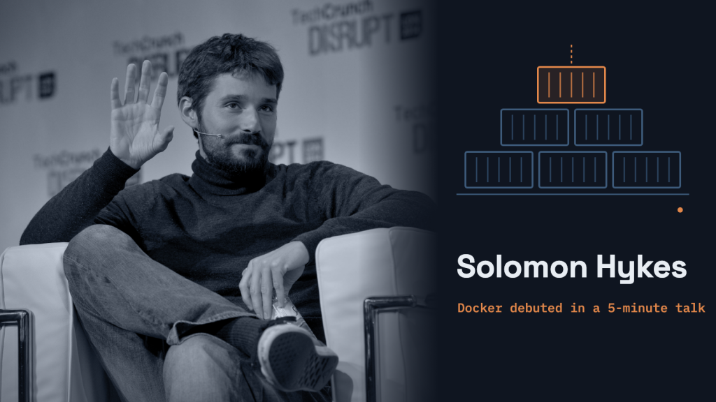 Solomon Hykes, seated on stage and raising one hand, beside a dark panel with a stack of shipping-container outlines and his name.