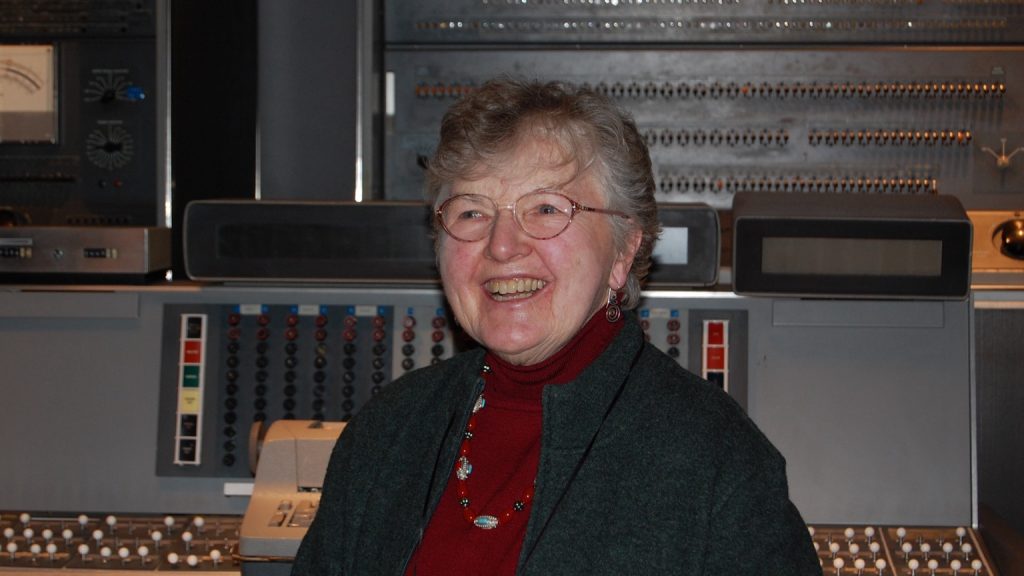 Computer scientist Frances Allen smiling in front of an IBM 7030 Stretch computer at the Computer History Museum in 2011.