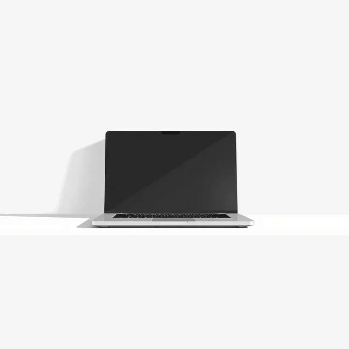 Une illustration minimaliste d'un ordinateur portable métallique ouvert projetant une ombre douce sur un fond en dégradé épuré.