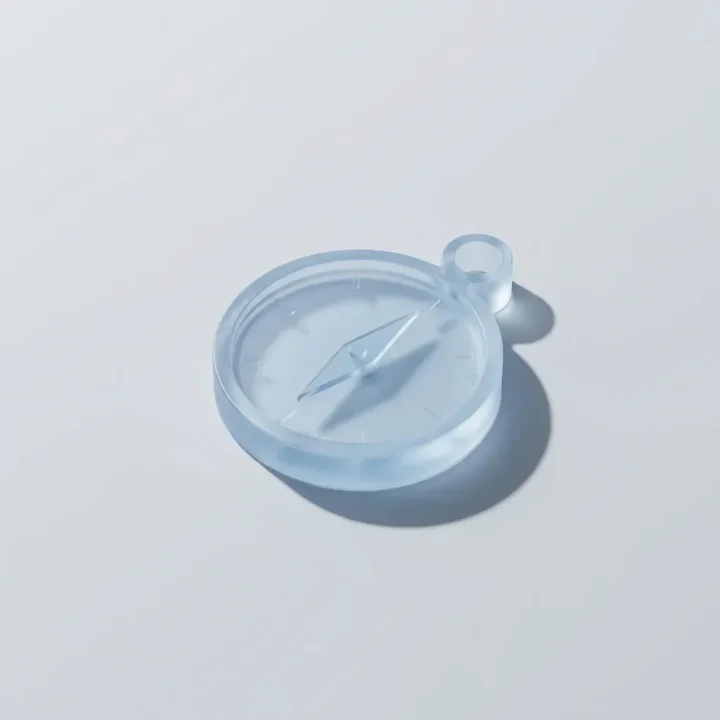 Un rendu 3D moderne d'une boussole translucide posée sur une surface claire sous un éclairage doux.